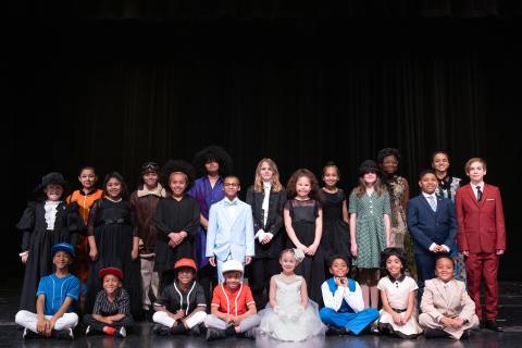group of students dressed in historical character attire standing together on a stage