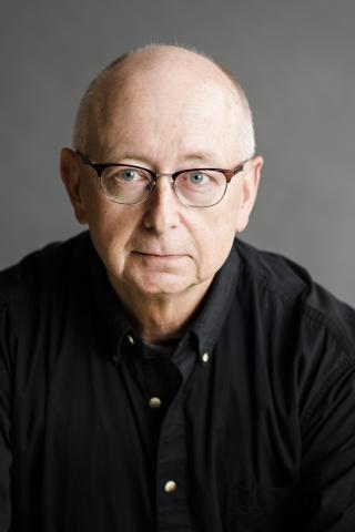 photo of a man with glasses and a black button down shirt.