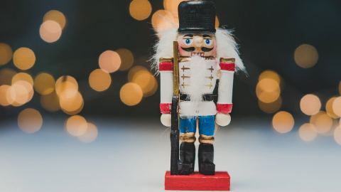 A wooden nutcracker in front of glowing, slightly blurry lights.