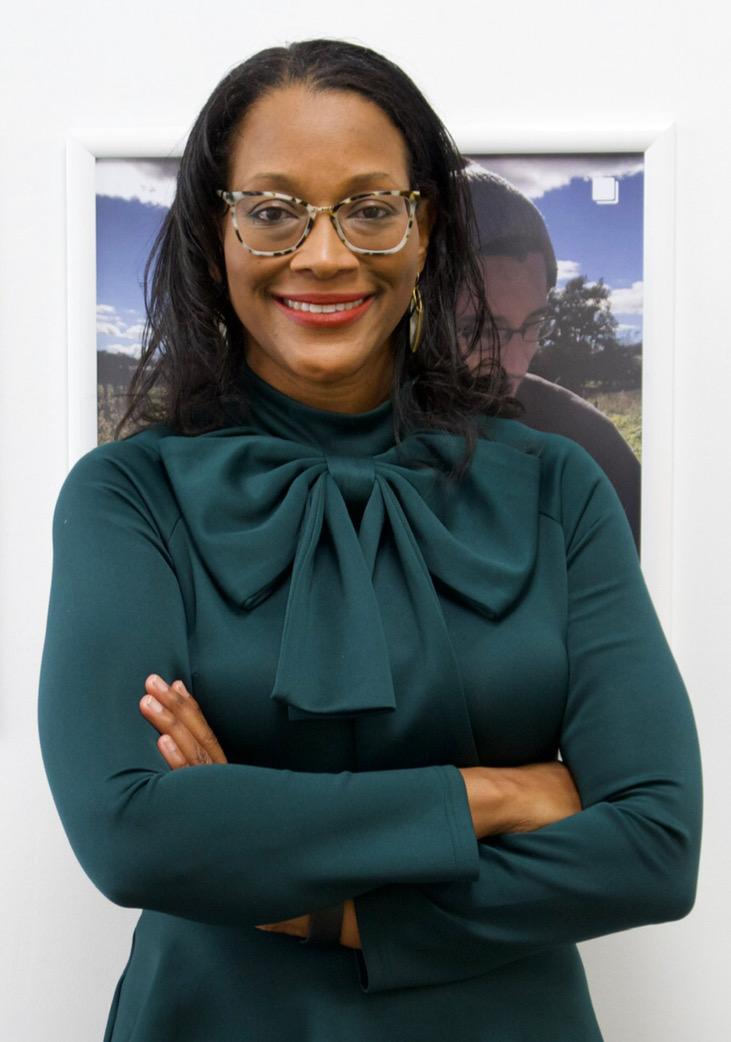 Headshot of woman in green top in front of a painting. 