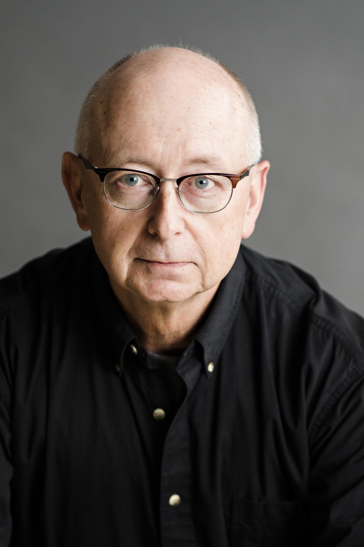 photo of a man with glasses and a black button down shirt.